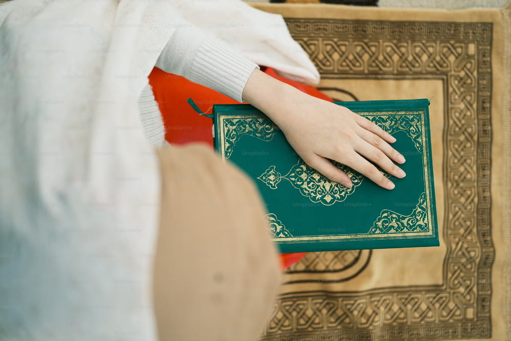 a person holding a green book with a gold border