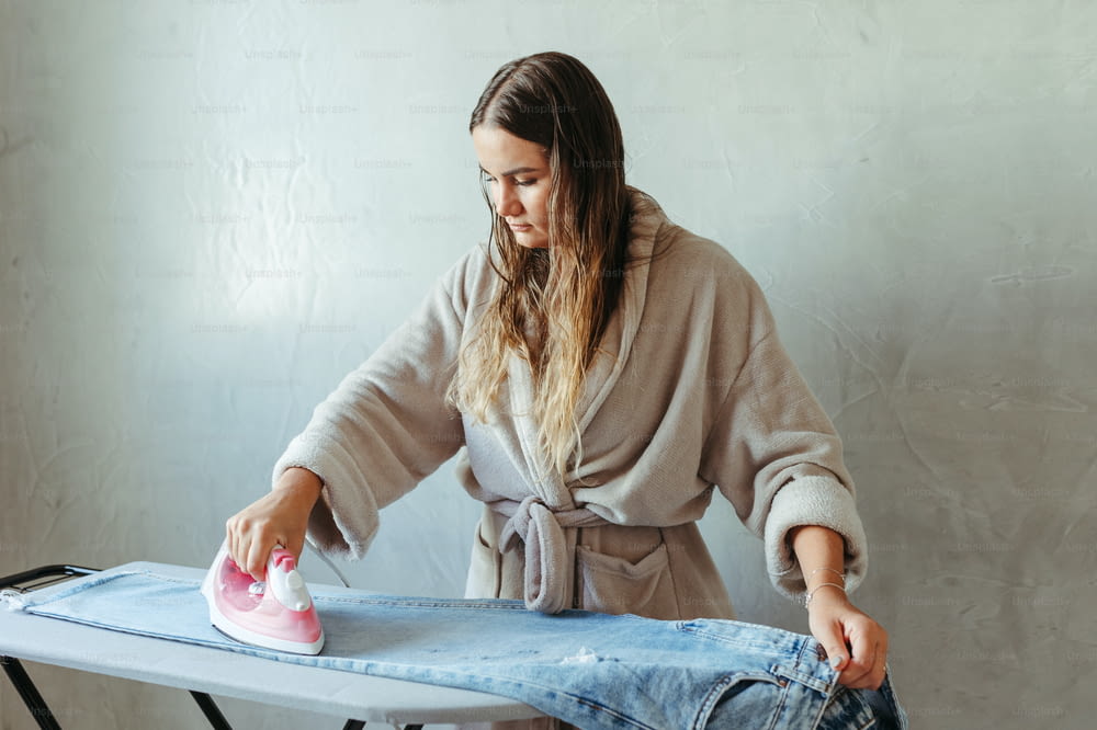 a woman ironing clothes on an ironing board