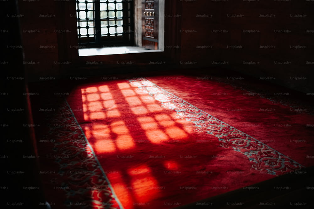 a room with a red rug and a window