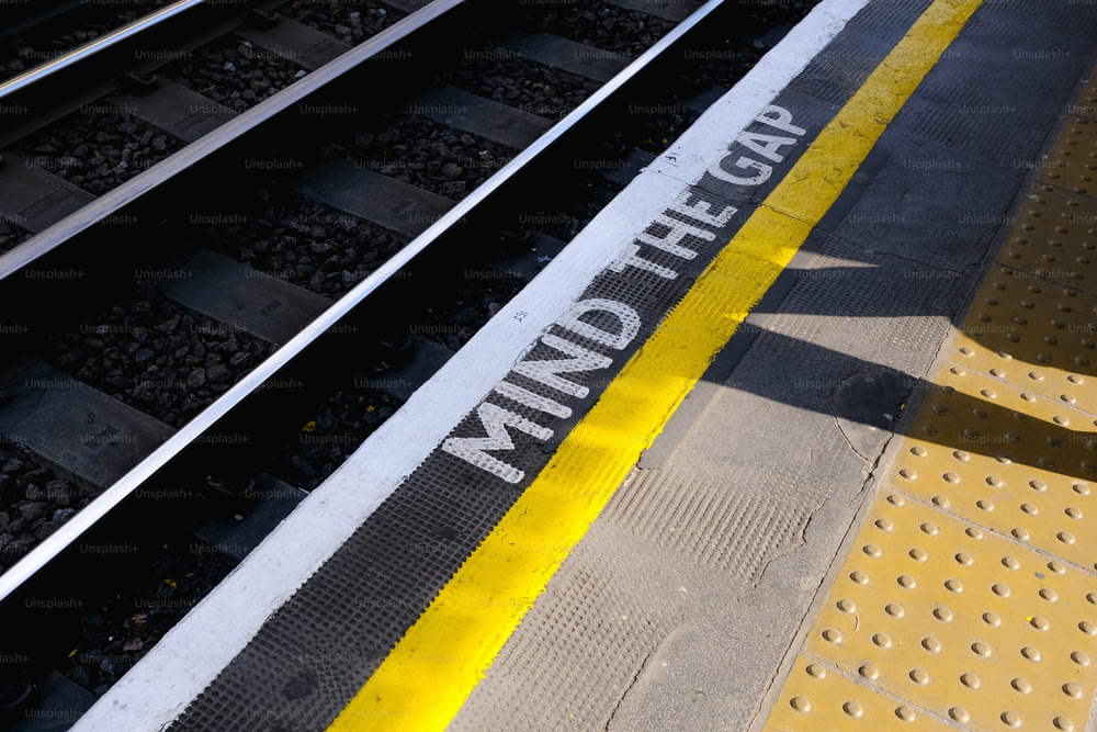 une voie ferrée avec une ligne jaune et un panneau indiquant l’écart