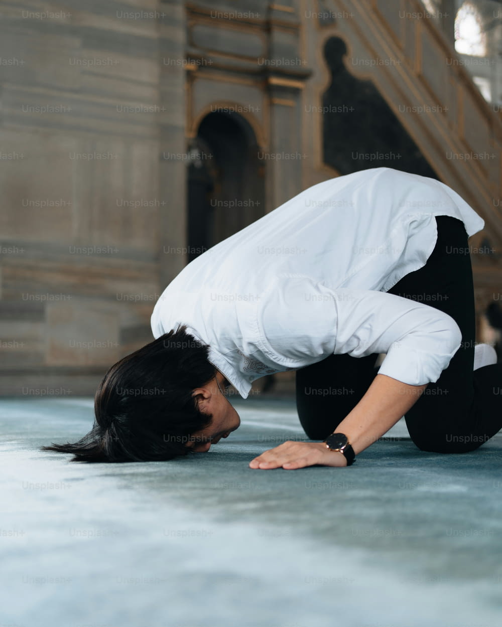 a woman in white shirt and black pants doing a handstand