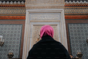 Une femme portant un foulard rose debout devant une porte