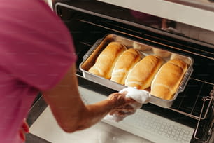 a person pulling bread out of an oven