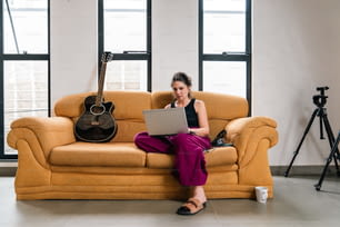 Una mujer sentada en un sofá usando una computadora portátil