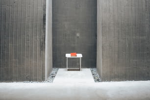 a small white table sitting in between two tall grey walls
