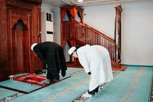 a couple of men standing over a rug on top of a floor