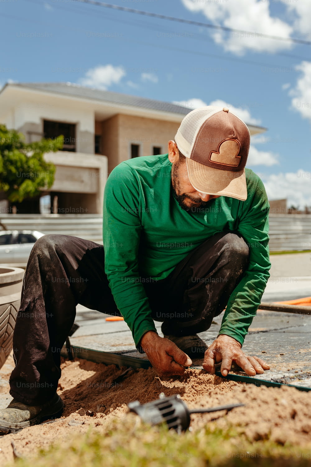 녹색 셔츠와 모자를 쓴 남자가 나무 조각을 작업하고 있다