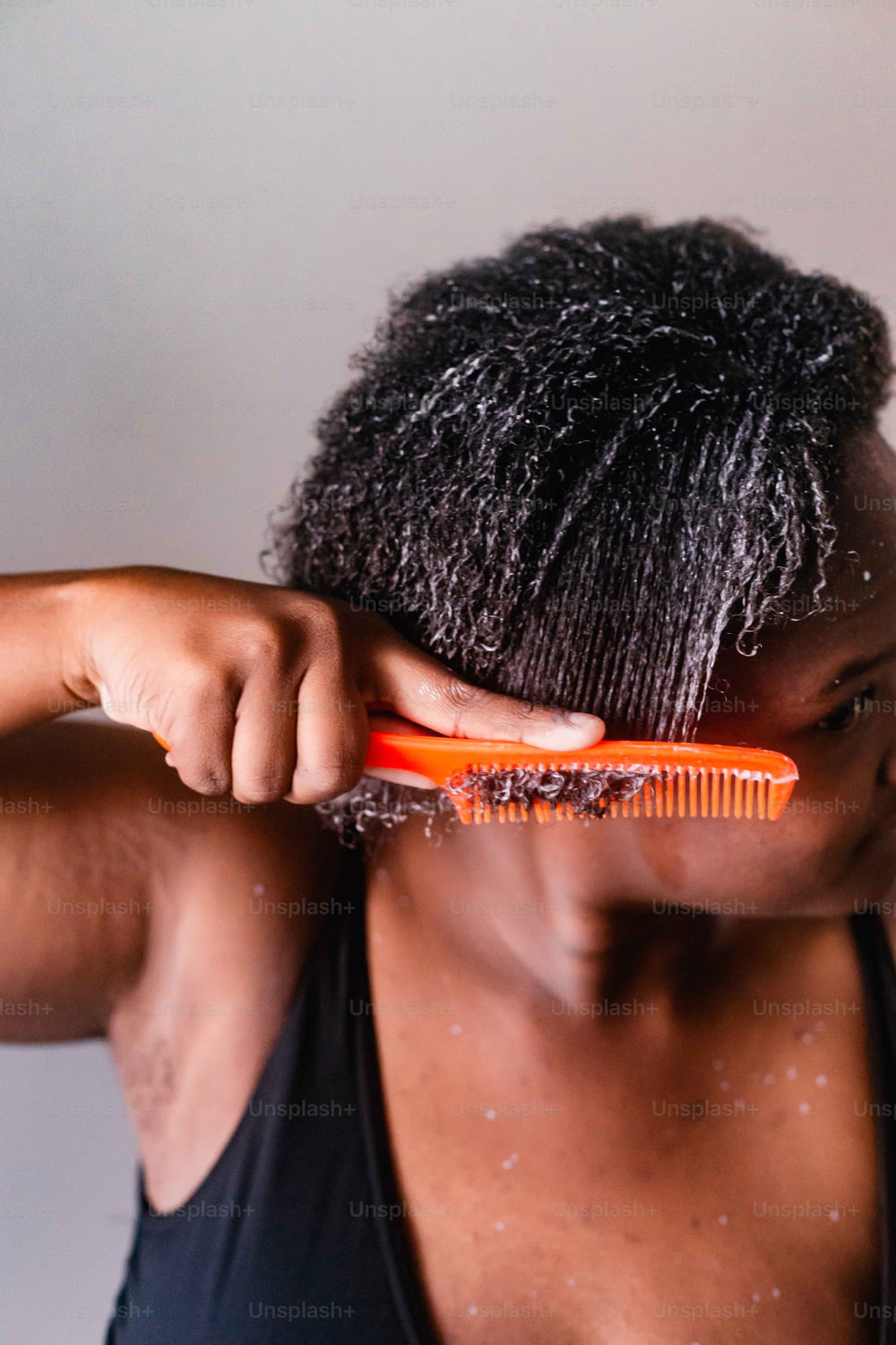 Un uomo si sta spazzolando i capelli con un pettine arancione