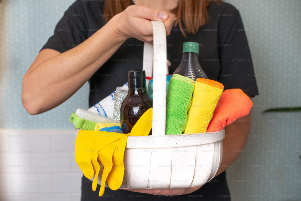 a woman holding a basket of cleaning supplies