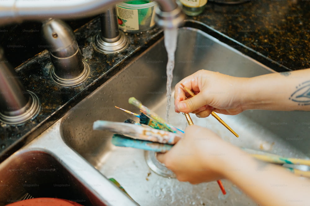 une personne qui se lave les mains avec une brosse à dents dans un évier