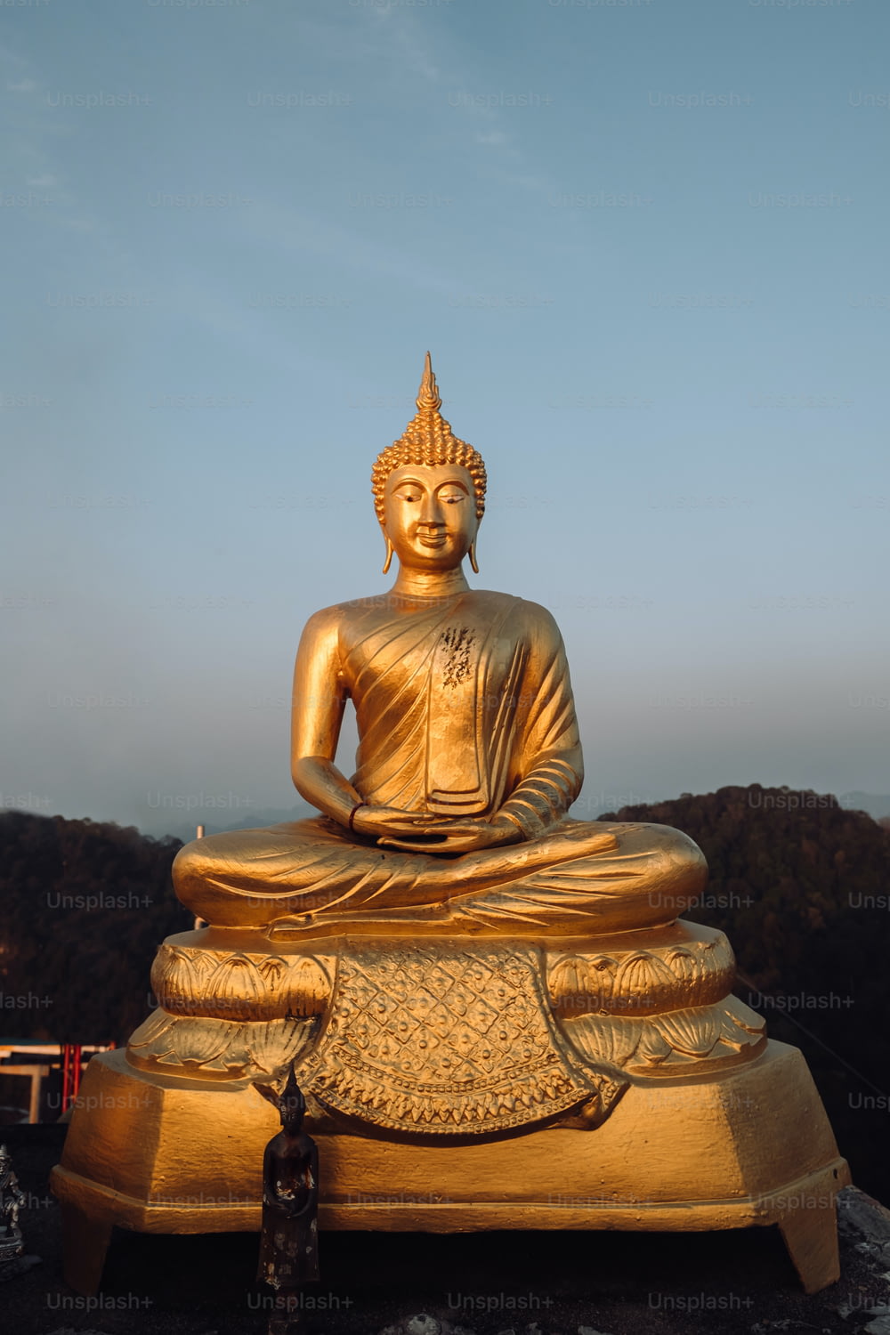 Une statue de Bouddha dorée assise au sommet d’un rocher