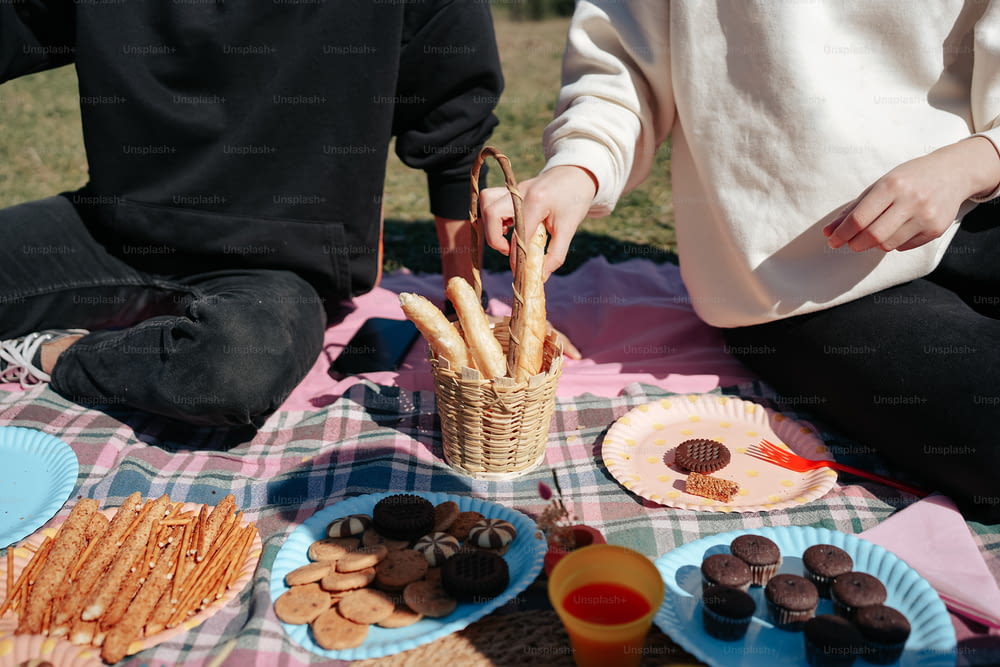 two people sitting at a picnic table with snacks