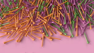 une pile de cure-dents colorés sur une surface rose