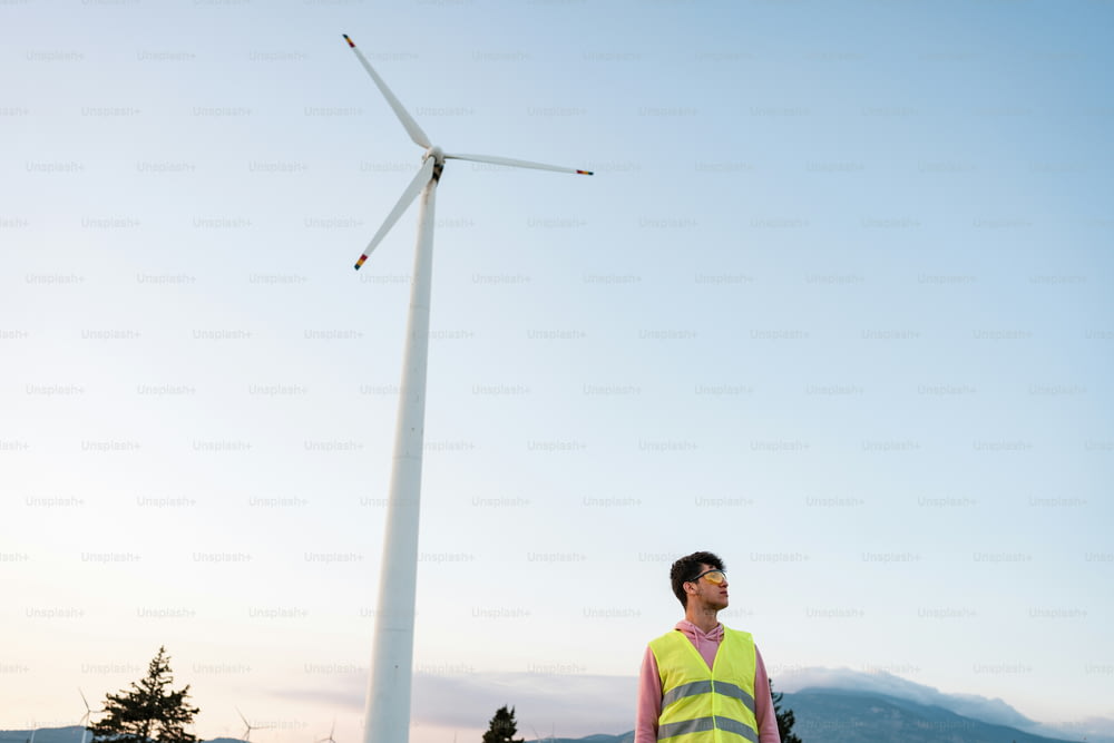 Un hombre parado junto a una turbina eólica
