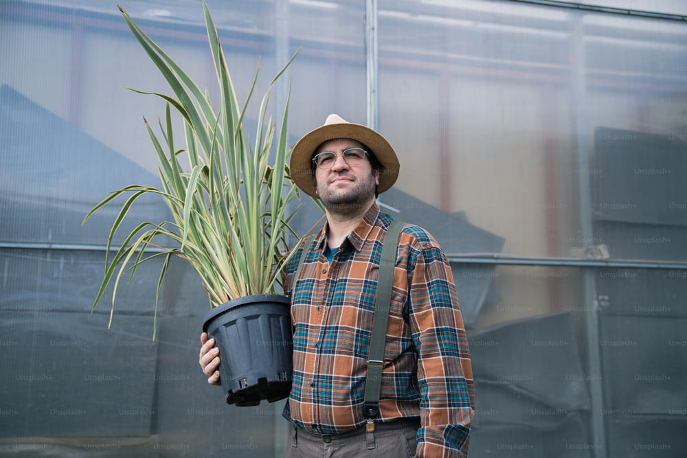a man wearing a hat holding a potted plant