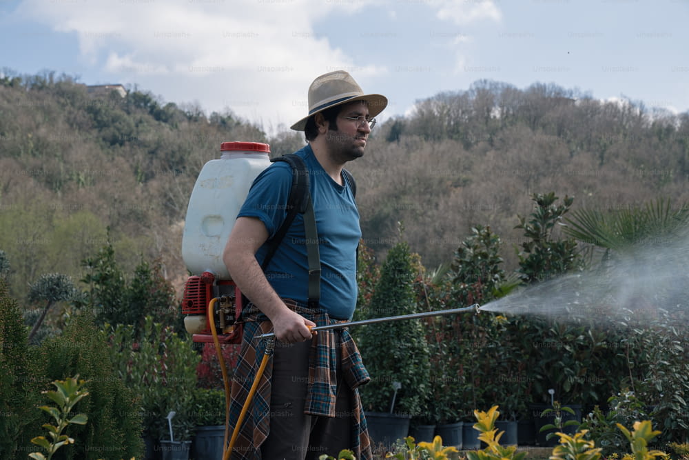 a man in a hat is spraying water on a field