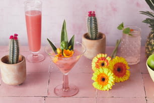 une table rose surmontée de trois verres remplis de boissons