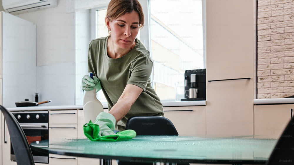 a woman cleaning a table with a green cloth