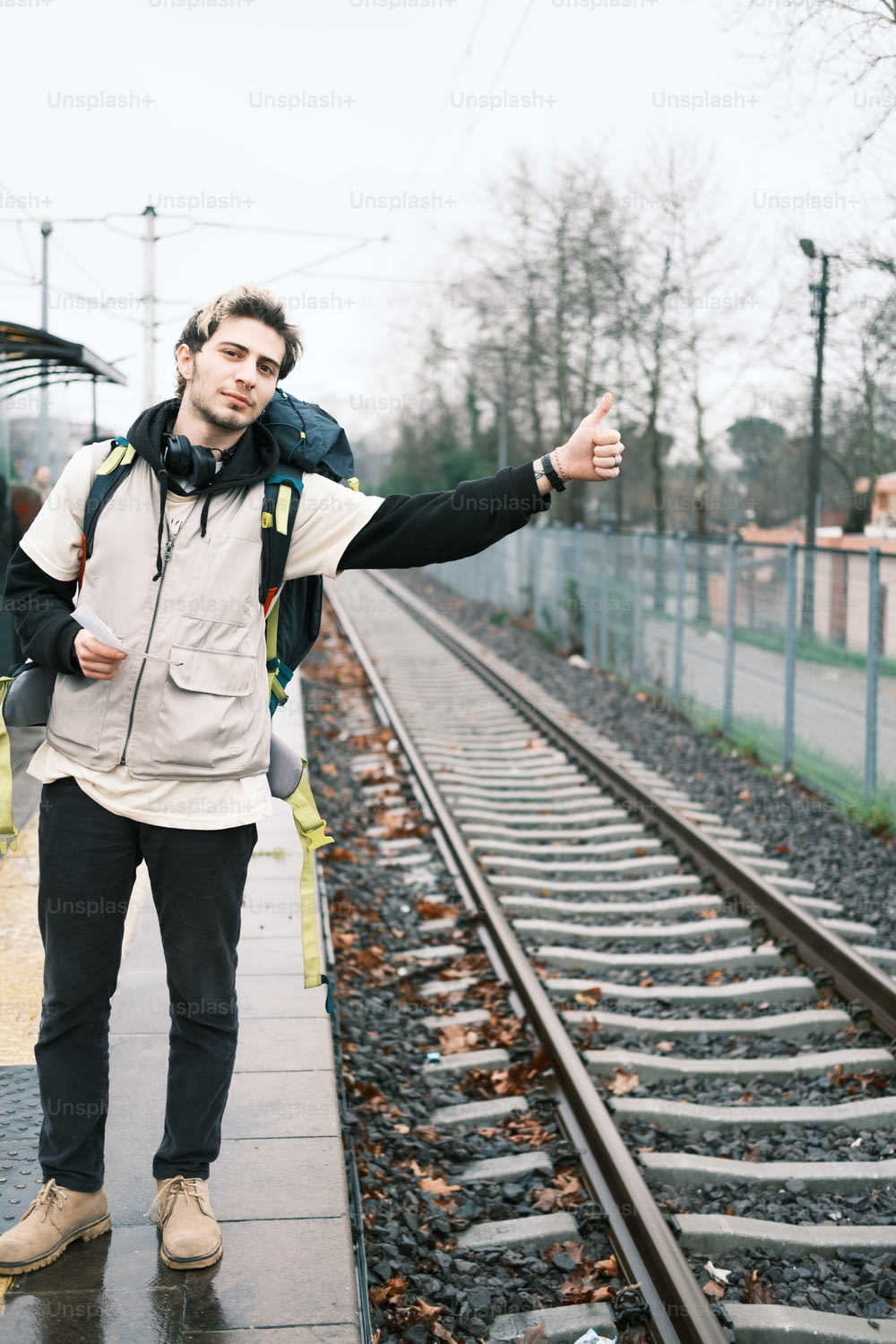 Un hombre parado en una vía de tren dando un pulgar hacia arriba