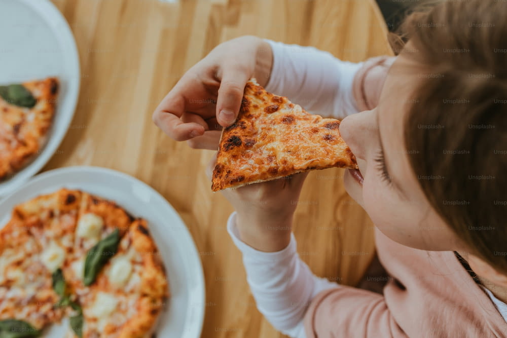 a young girl eating a slice of pizza