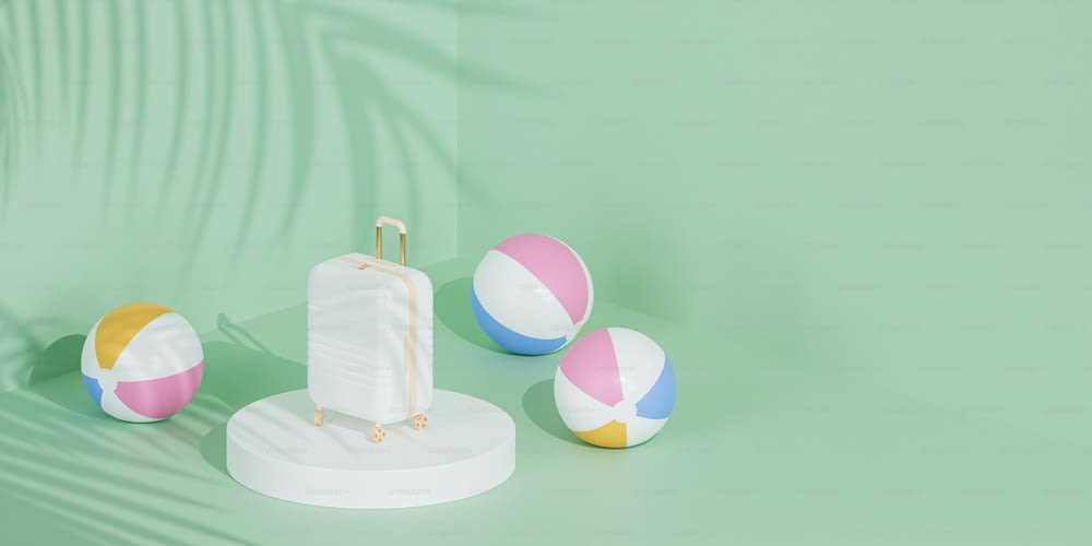 three beach balls and a suitcase on a green background