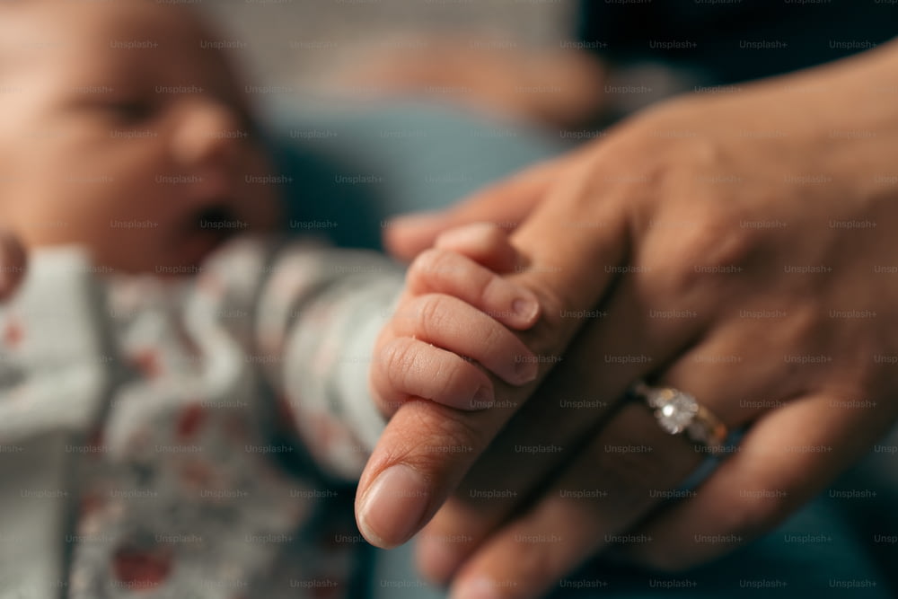 uma pessoa segurando a mão de um bebê com um anel sobre ele