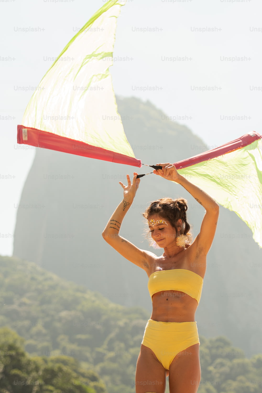a woman in a yellow bikini holding a kite
