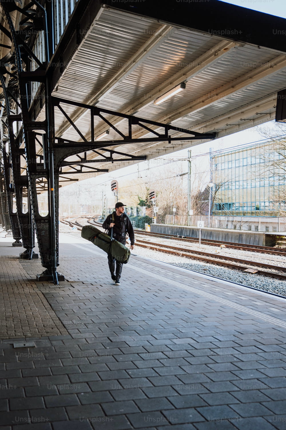 a man with a surfboard walking down a train platform
