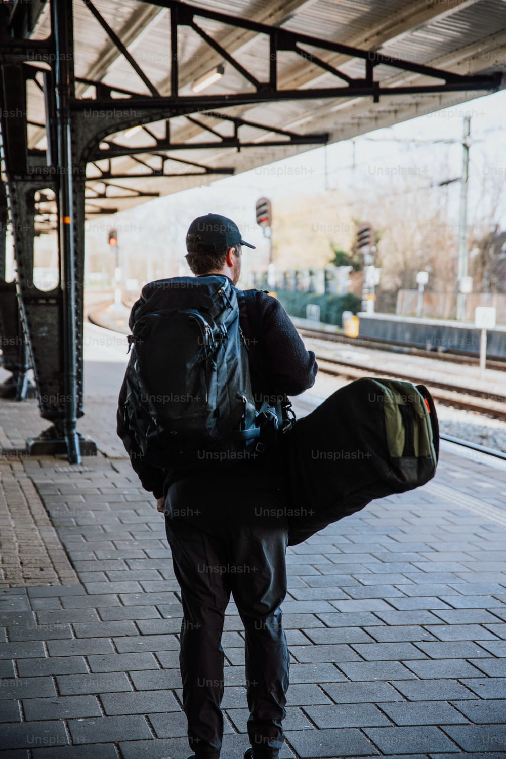 Un uomo con uno zaino che cammina lungo una piattaforma del treno