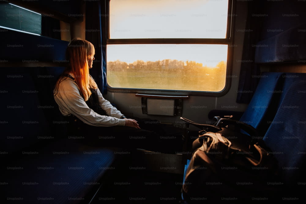 Una mujer sentada en un tren mirando por la ventana