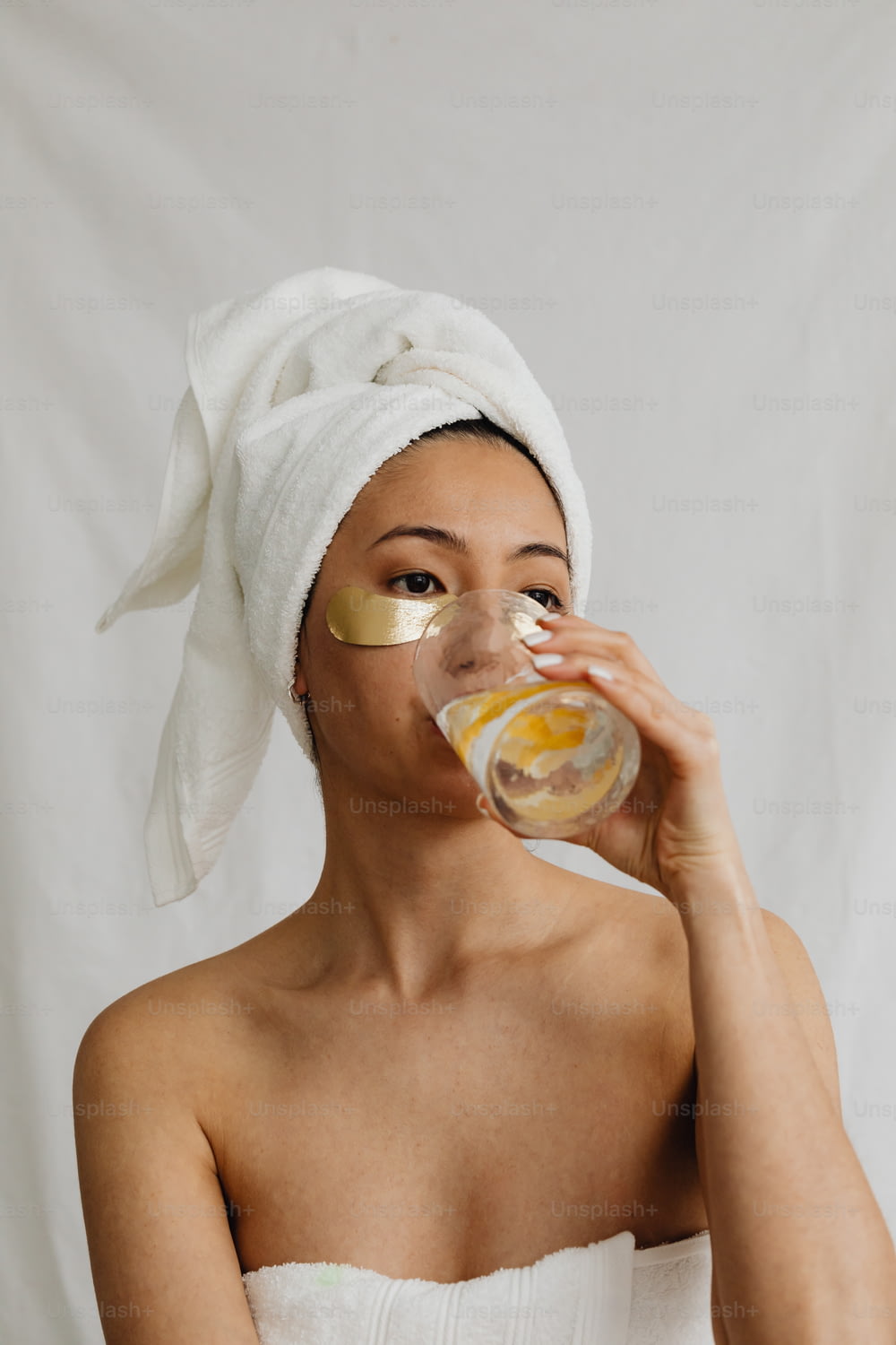 a woman with a towel on her head drinking from a glass