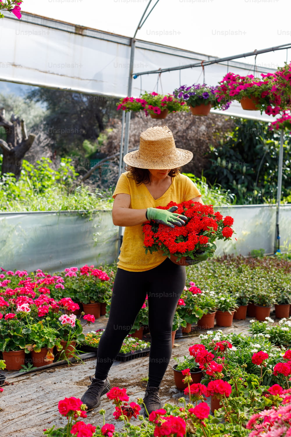 a woman in a yellow shirt and hat holding a bunch of flowers