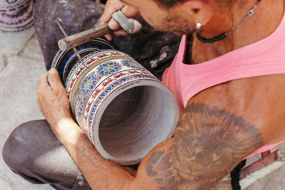 a man with tattoos on his arm holding a cup