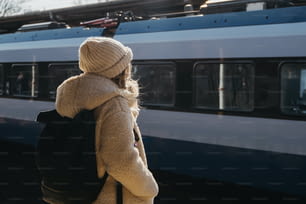 Una mujer con una mochila parada frente a un tren