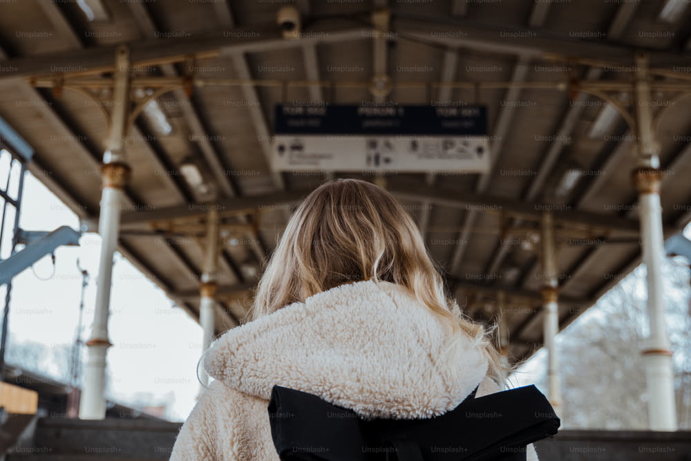 a woman in a white coat is waiting for a train