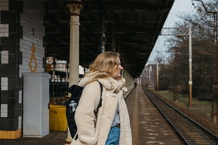 Una donna in piedi su una piattaforma del treno accanto a un treno