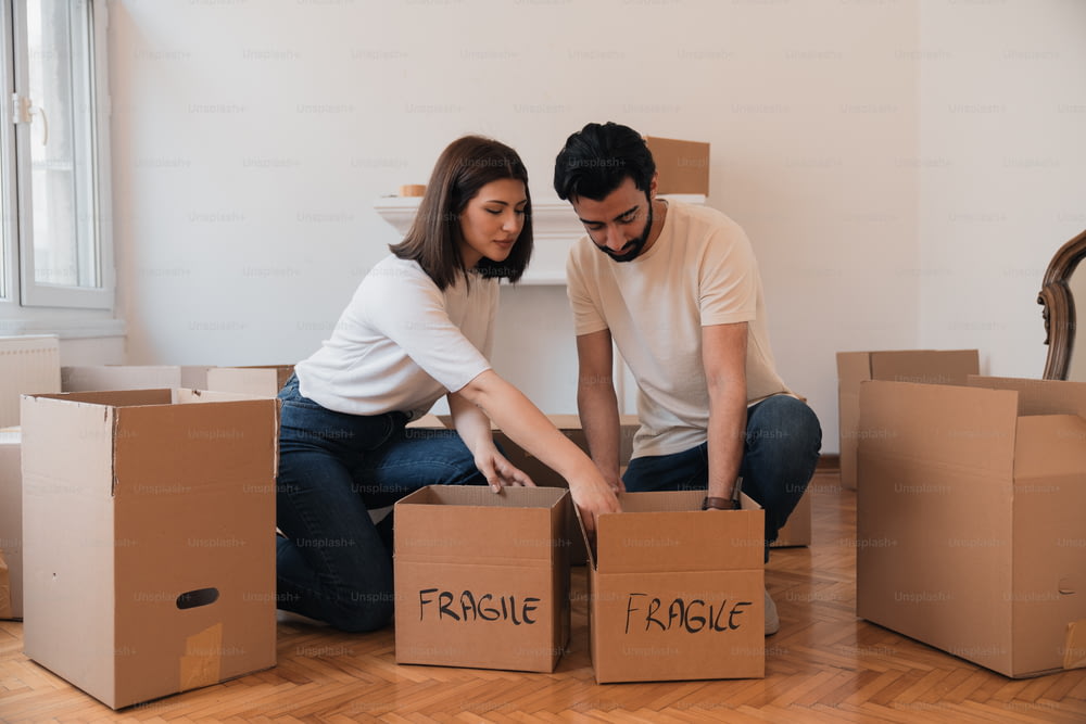 a man and a woman sitting on the floor with boxes
