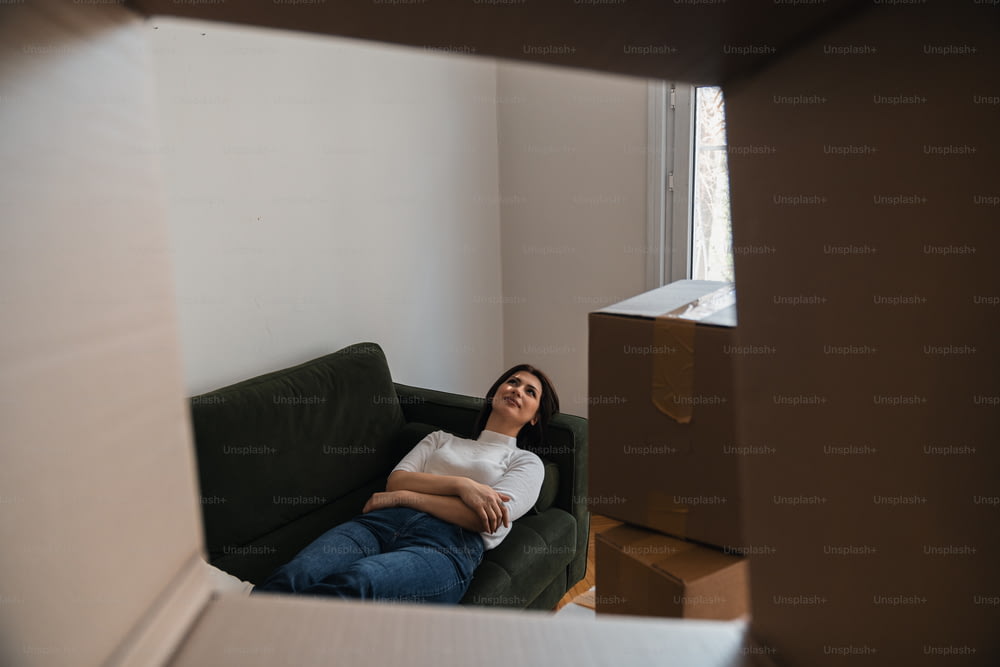Une femme assise sur un canapé dans une pièce avec des boîtes