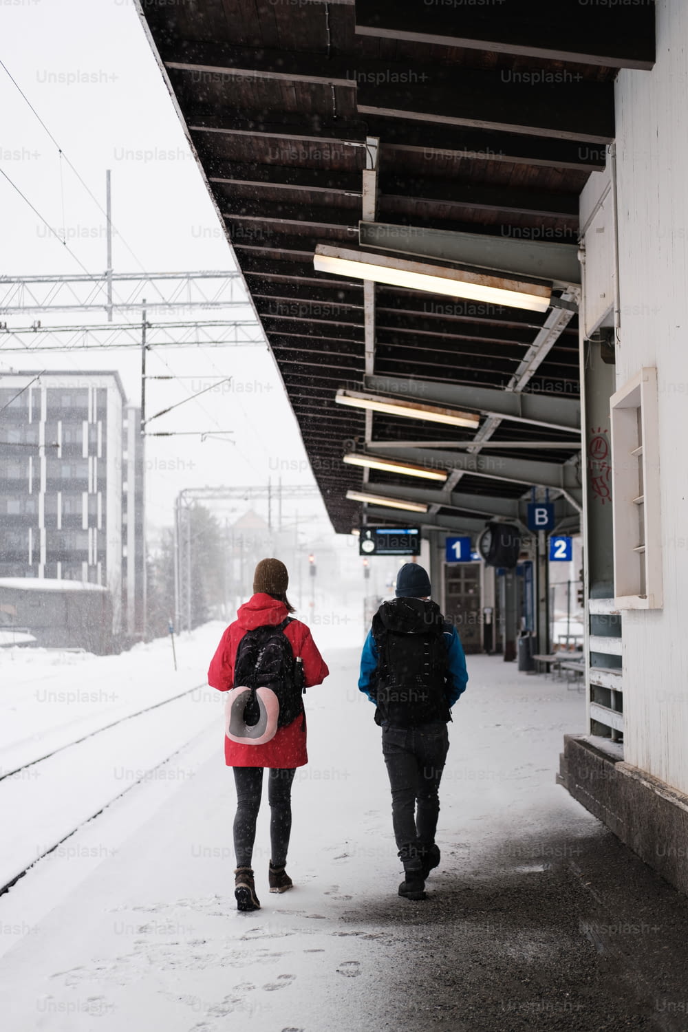 um casal de pessoas andando por uma calçada coberta de neve