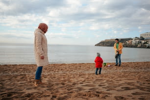 ビーチに立つ女性と2人の子供