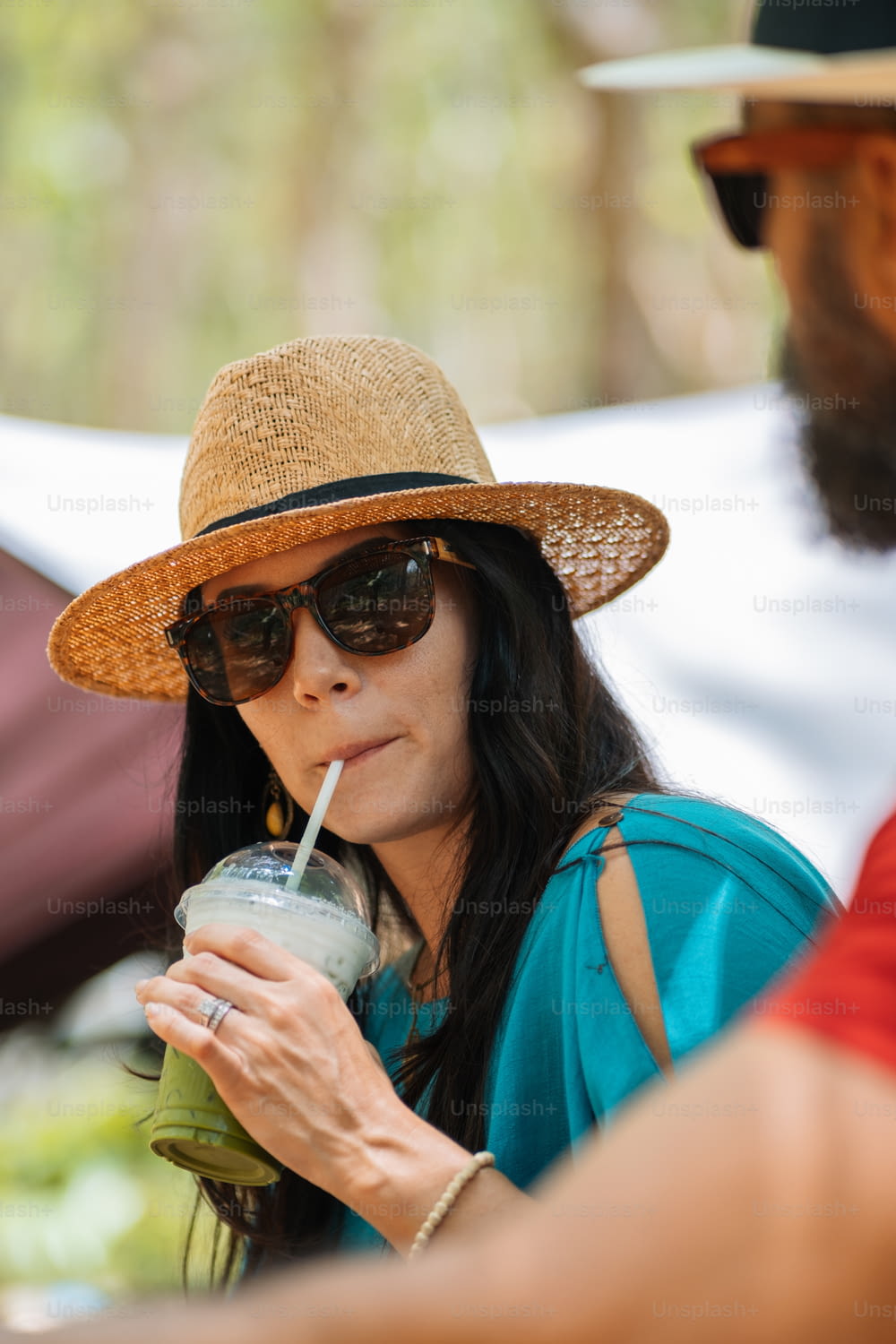 uma mulher em um chapéu de palha bebendo uma bebida