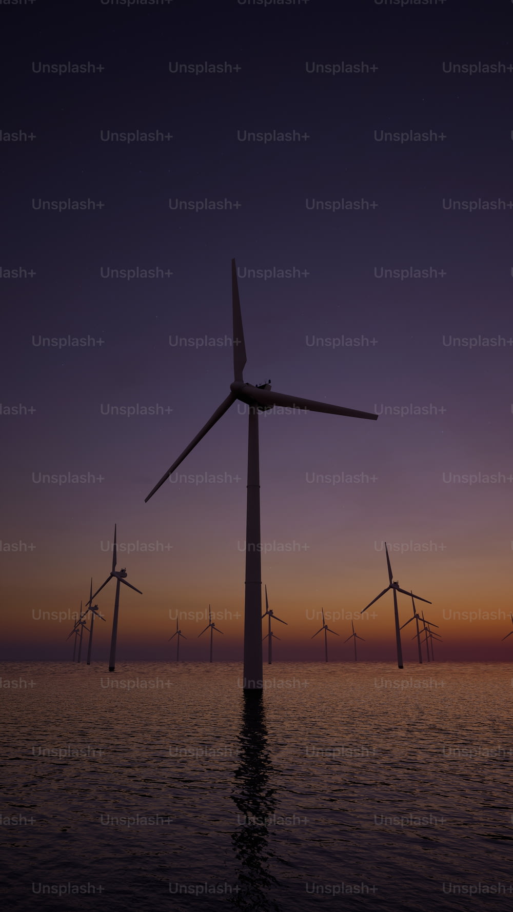 a group of windmills floating in the ocean at sunset