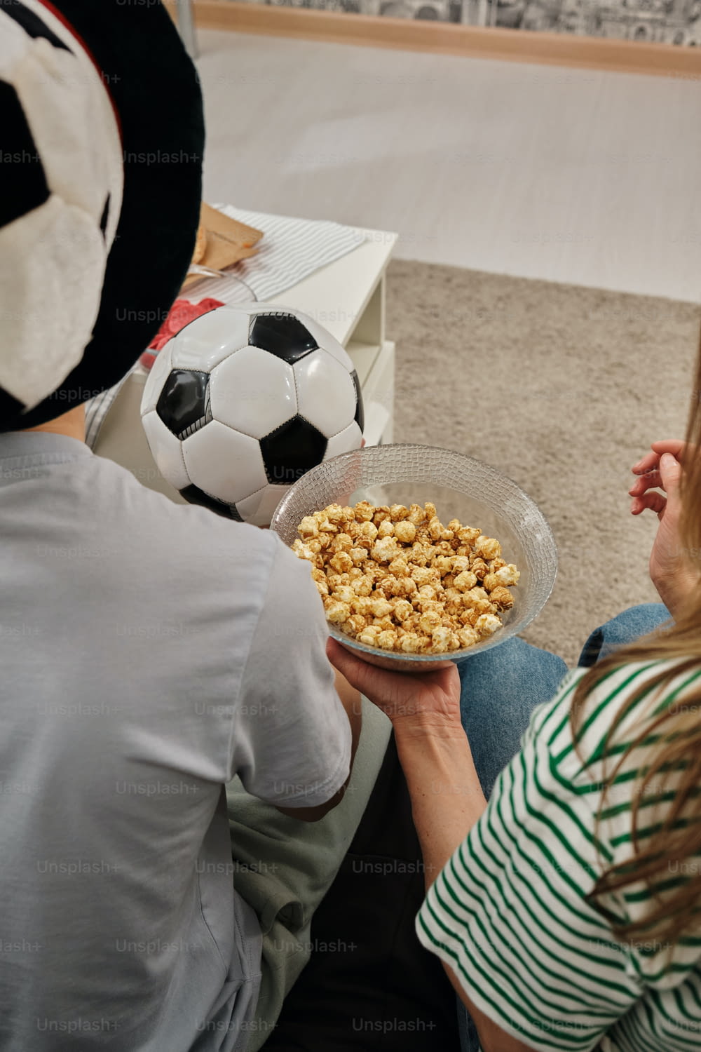 a man and a woman sitting on the floor holding a bowl of cereal
