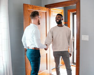 two men shaking hands in front of a door