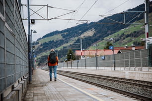 Un uomo che cammina lungo un binario del treno vicino a una stazione ferroviaria