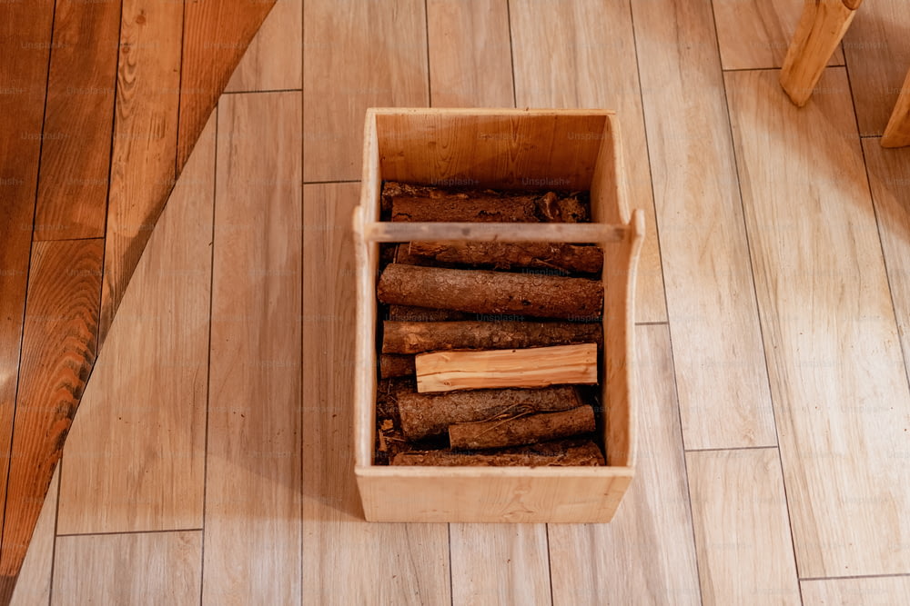 Una caja de madera llena de troncos encima de un piso de madera