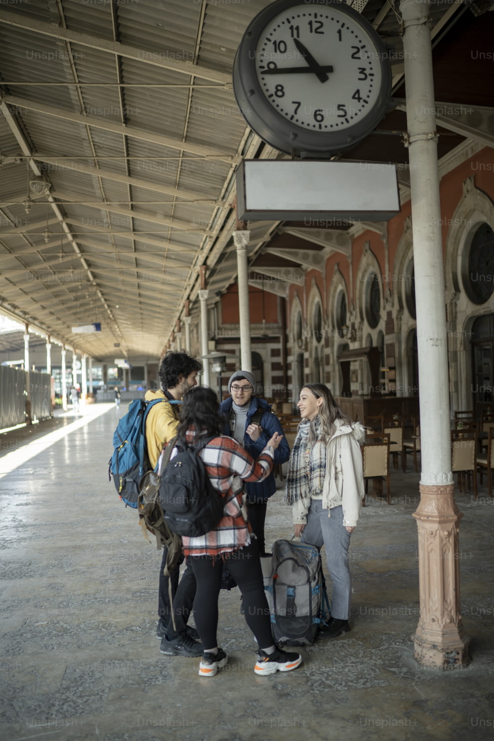 un groupe de personnes debout sous une horloge dans une gare
