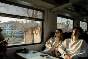 Un uomo e una donna seduti su un treno che guardano fuori dal finestrino