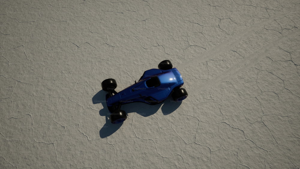 Una macchinina giocattolo blu seduta sulla cima di una spiaggia sabbiosa