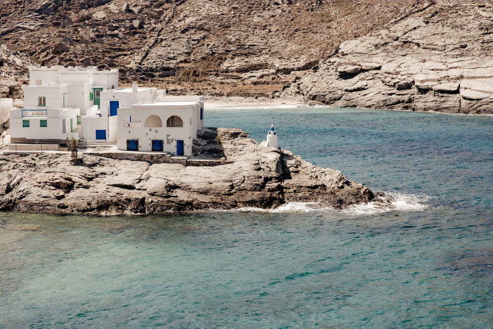 a white building sitting on top of a rocky cliff next to a body of water